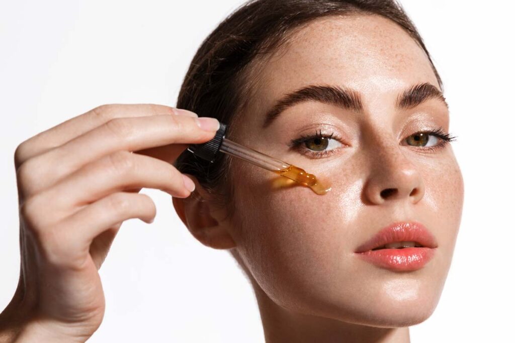 Close up of a woman putting Vitamin C serrum on her face, representing the Dr. Dennis Gross Skincare settlement.