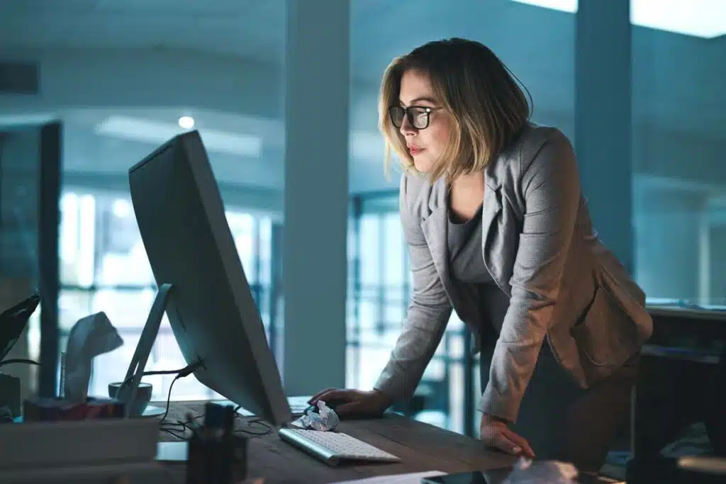 A woman looking at her computer screen in the office, representing the [24]7.ai settlement.