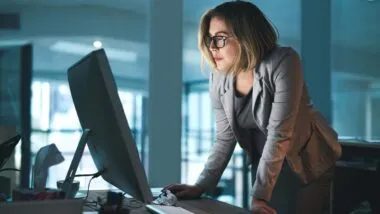 A woman looking at her computer screen in the office, representing the [24]7.ai settlement.