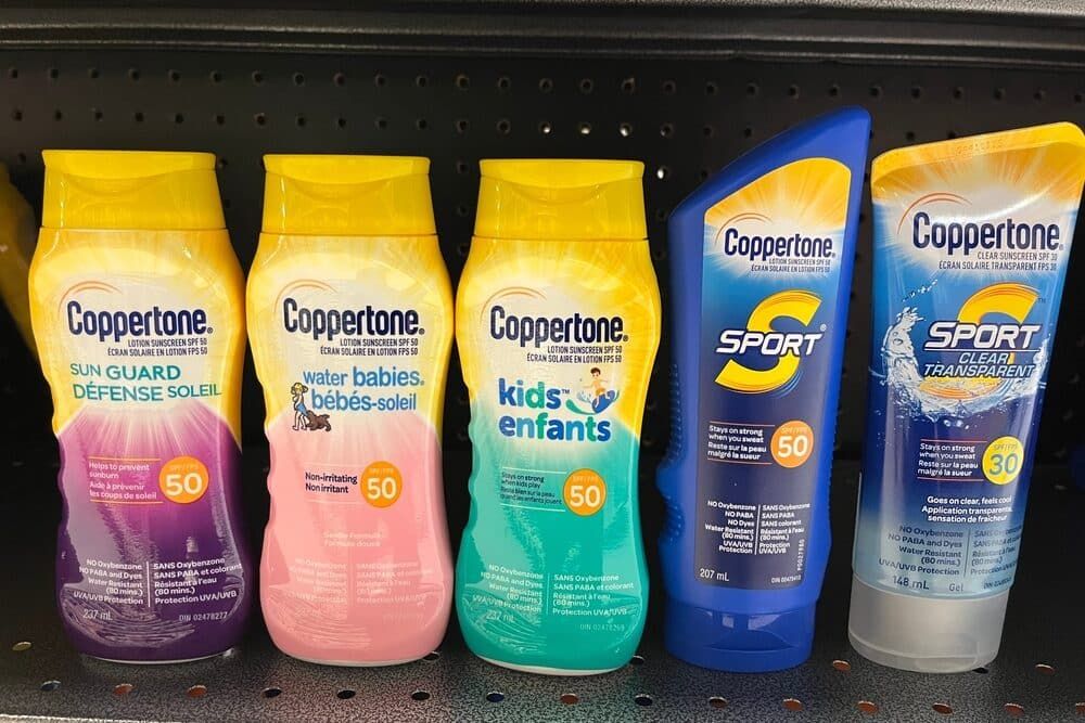 Bottles of various types of Coppertone sunscreen on a pharmacy shelf.