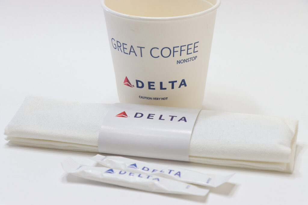 A cup of coffee with Delta logos on it representing the Delta hot coffee lawsuit.