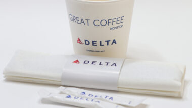 A cup of coffee with Delta logos on it representing the Delta hot coffee lawsuit.