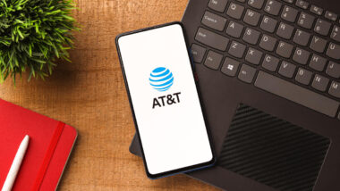 At&t logo on cell phone laying on a computer representing the AT&T data breach.