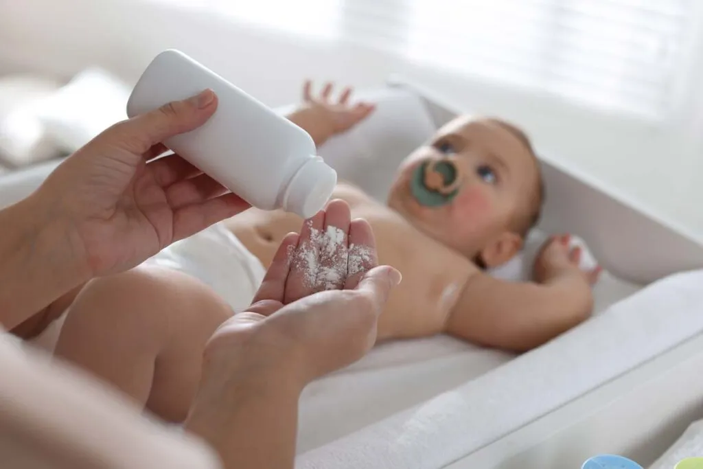 Close up of a mother putting baby powder in her hand, representing the baby powder recall.