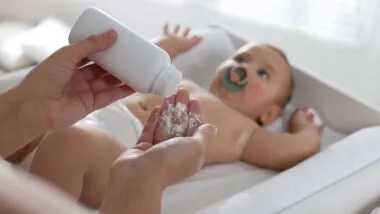 Close up of a mother putting baby powder in her hand, representing the baby powder recall.