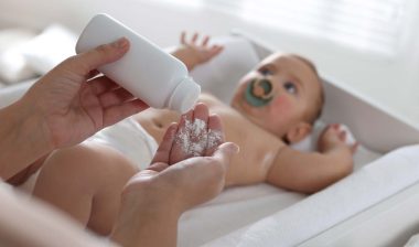 Close up of a mother putting baby powder in her hand, representing the baby powder recall.