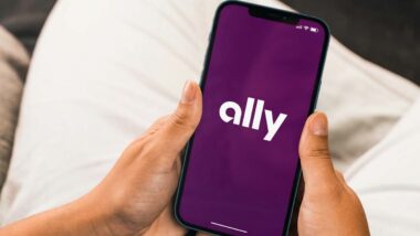 Close up of hands holding a smartphone with Ally logo displayed, representing the Ally Bank class action.