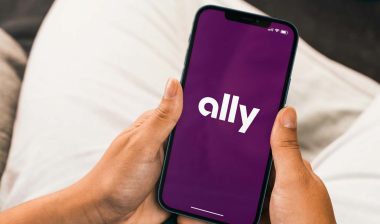 Close up of hands holding a smartphone with Ally logo displayed, representing the Ally Bank class action.