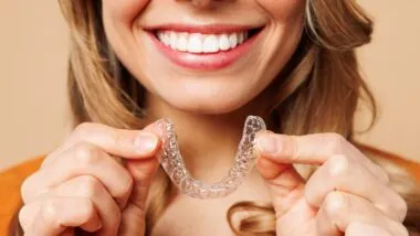 woman using invisalign silicone teeth trainer representing representing the Invisalign class actions.