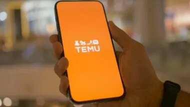 Close up of hand holding a smartphone with Temu logo displayed, representing the Temu data breach.