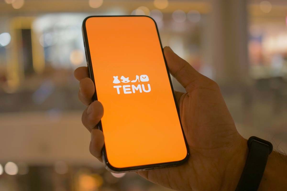 Close up of hand holding a smartphone with Temu logo displayed, representing the Temu data breach.