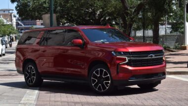 A red metallic Chevrolet Tahoe driving along a road, representing the GM recall.