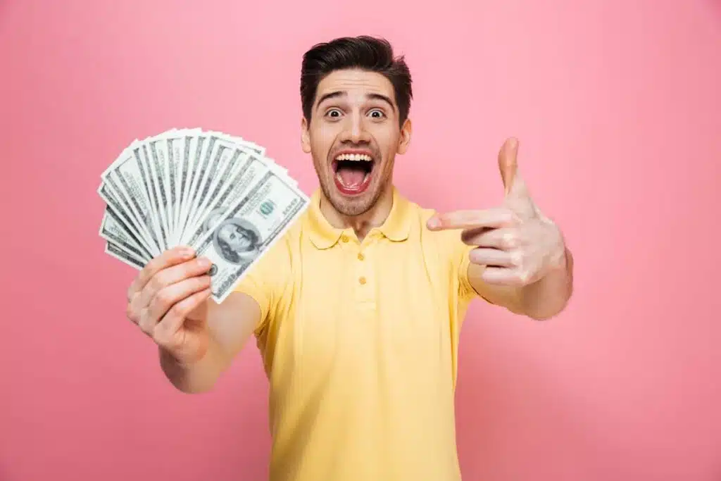 An excited man holding U.S. cash, representing FTC refunds.