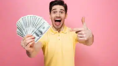An excited man holding U.S. cash, representing FTC refunds.