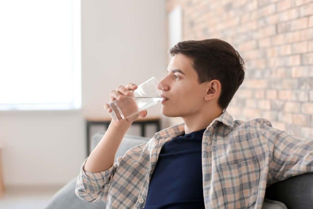 A young man drinking water from a glass, representing the PFAS class action.