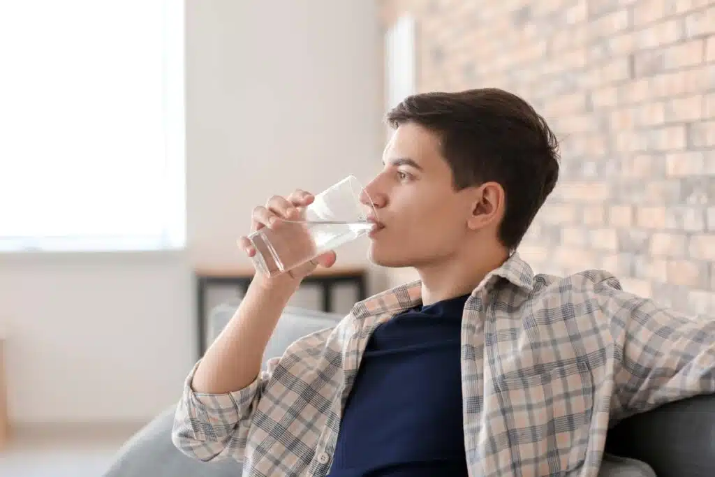 A young man drinking water from a glass, representing the PFAS class action.