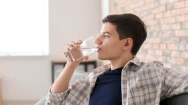 A young man drinking water from a glass, representing the PFAS class action.