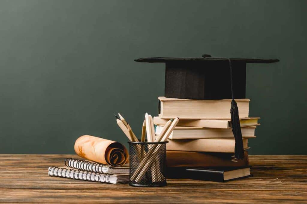 College books and graduation cap on a table, representing school prices.