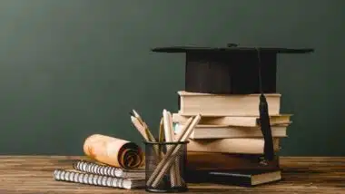 College books and graduation cap on a table, representing school prices.