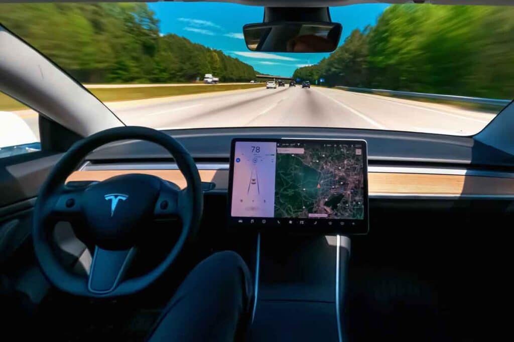 Interior of a Tesla in self driving mode, representing the NHTSA investigation.