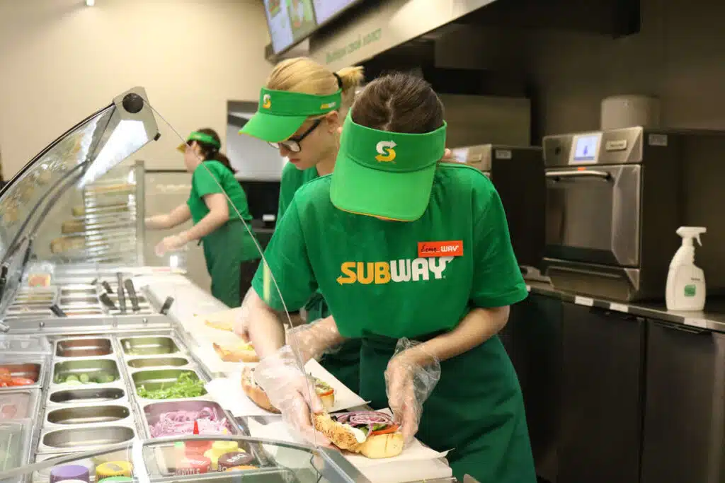 A sandwich artist making a subway sandwich representing the Subway class action.