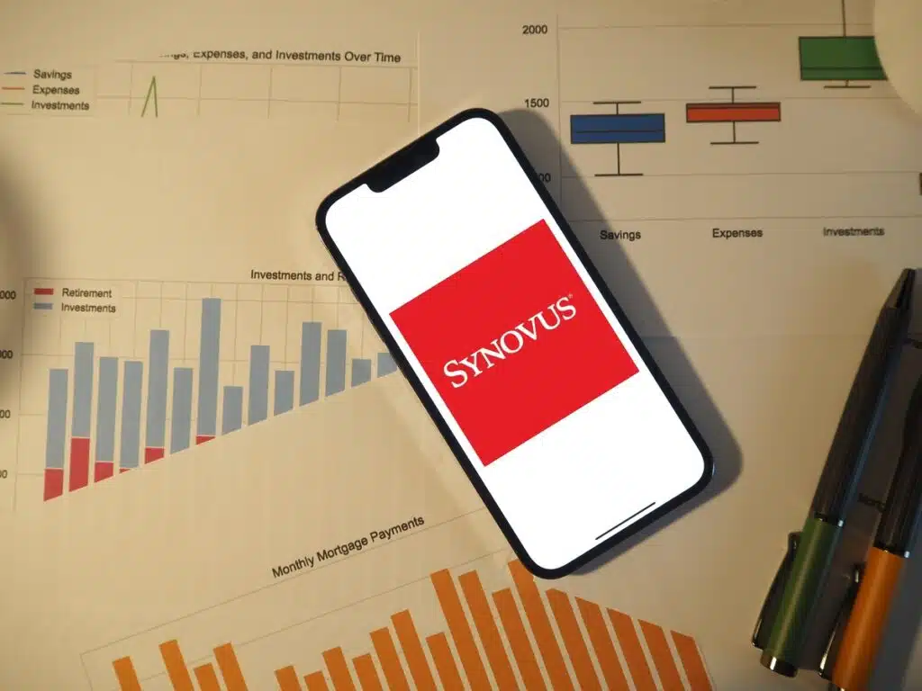 Synovus Bank logo on a cell phone on top of spreadsheets representing the Snyovus Bank class action.