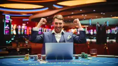 Portrait of a Happy Young Man in a Suit Using a Laptop Computer in Casino.