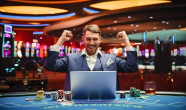 Portrait of a Happy Young Man in a Suit Using a Laptop Computer in Casino.