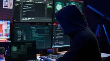 A hooded hacker using a computer, representing the Behavioral Health Group settlement.