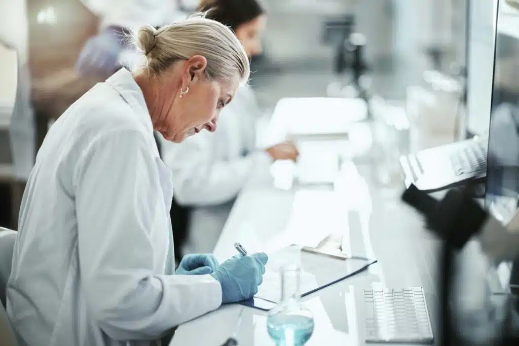 A clinical trial lab worker writing on a clipboard, representing the Cassava settlement.