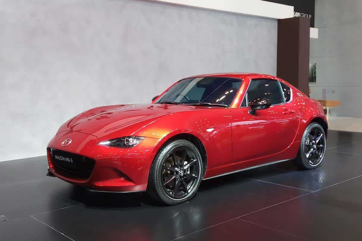 A red Mazda Miata at a car show, representing the Mazda recall.