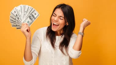 Girl holding cash with a yellow background representing recent settlement checks in the mail.