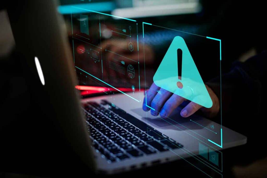 Close up of hands typing on a keyboard with a warning symbol overlay, representing the Ardagh Glass settlement.