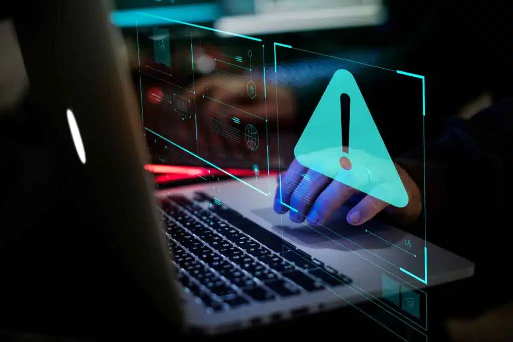 Close up of hands typing on a keyboard with a warning symbol overlay, representing the Ardagh Glass settlement.