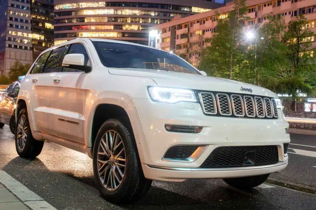 A white Jeep Grand Cherokee parked a city, representing the Stellantis recall.