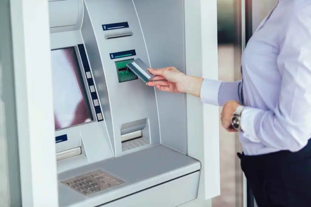 A business woman using an ATM, representing banking settlements.