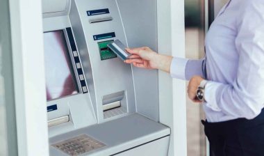 A business woman using an ATM, representing banking settlements.