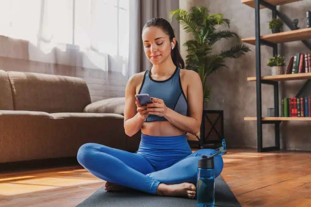 A woman in workout clothes using her phone, representing the Alo settlement.