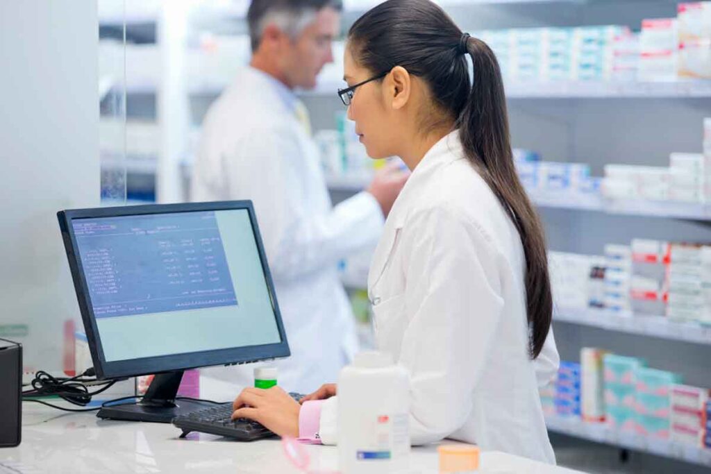 A pharmacist typing on a computer, representing the Injured Workers Pharmacy settlement.