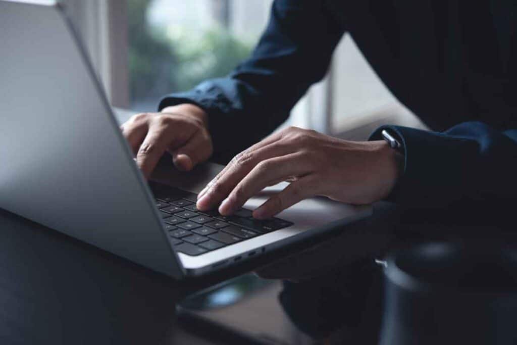 Close up of mans hands typing on a laptop, representing the Systems East settlement.