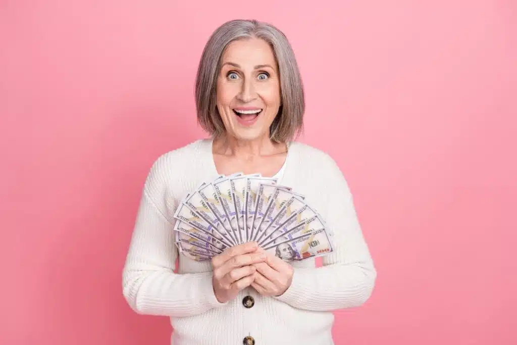 Happy middle aged woman holding cash representing checks in the mail.