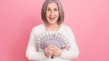 Happy middle aged woman holding cash representing checks in the mail.