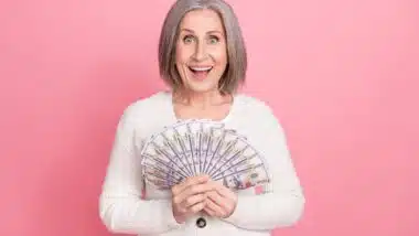 Happy middle aged woman holding cash representing checks in the mail.