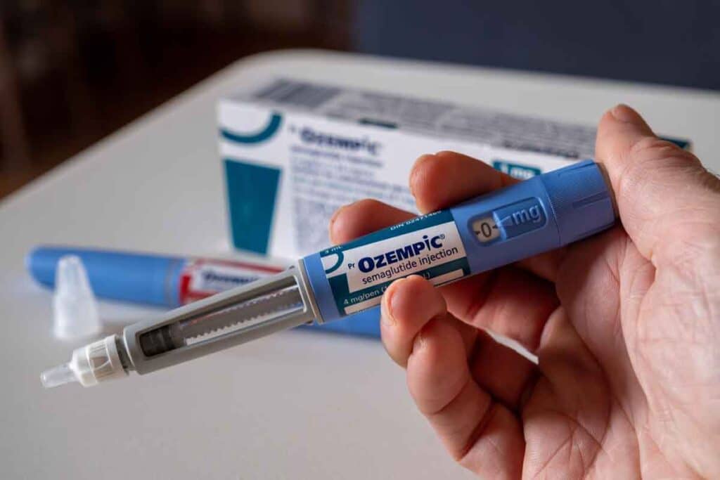 Hand holding Ozempic injection pen, representing weight loss drug risks.