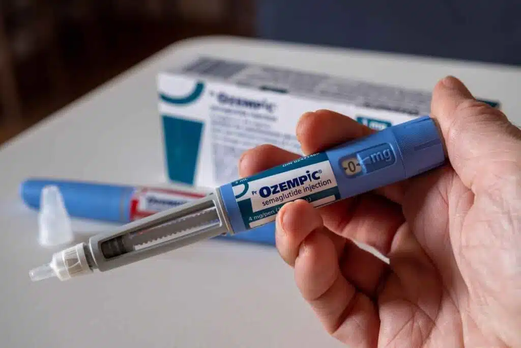 Hand holding Ozempic injection pen, representing weight loss drug risks.