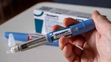 Hand holding Ozempic injection pen, representing weight loss drug risks.