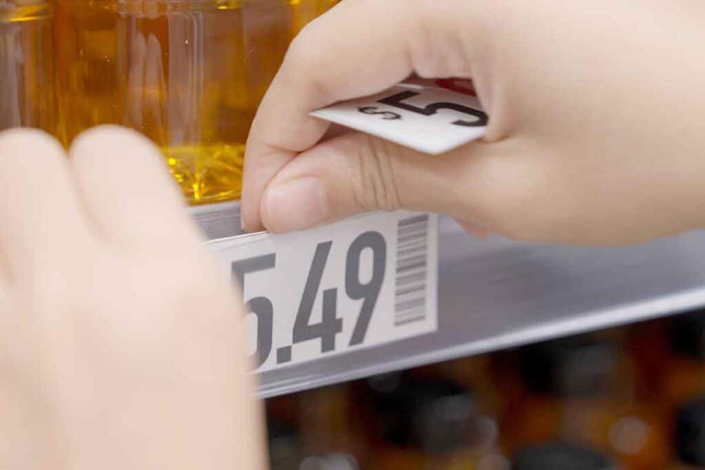 Close up of hands changing a price tag, representing false reference prices.