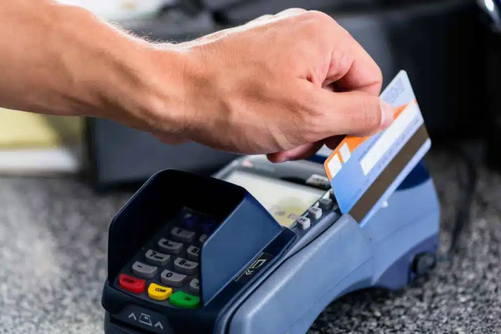 Close up of a hand swiping a bank card on a terminal, representing the Trustco Bank settlement.