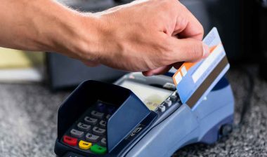 Close up of a hand swiping a bank card on a terminal, representing the Trustco Bank settlement.