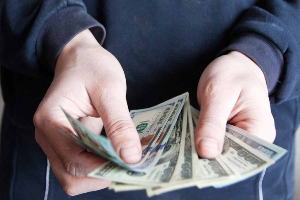 Close up of hands counting U.S. cash, representing FTC refunds.